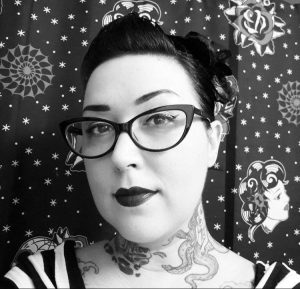 Woman with vintage hairstyle and tattoos poses against starry background