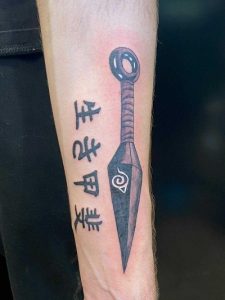 Forearm shows a black ink tattoo of a kunai with a spiral design and Japanese text.