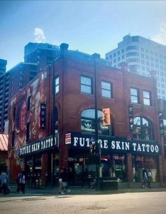 Brick building displaying FUTURE SKIN TATTOO signage, with window signs for TATTOO, PIERCING, and LASER REMOVAL.