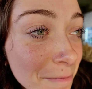 Close-up of a woman's face with a small silver nose stud piercing.