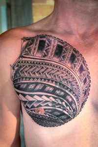 Person's chest features a large, circular tribal tattoo in black ink.