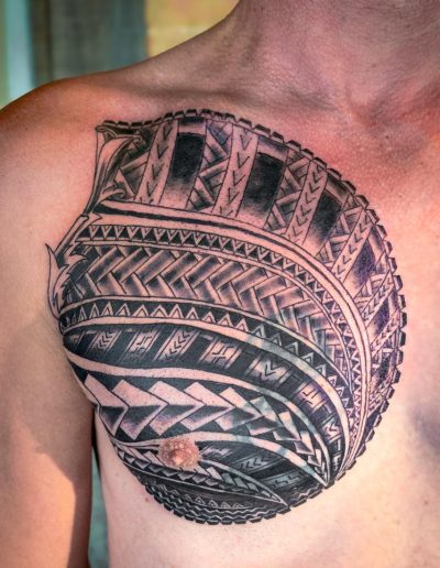 Person's chest features a large, circular tribal tattoo in black ink.