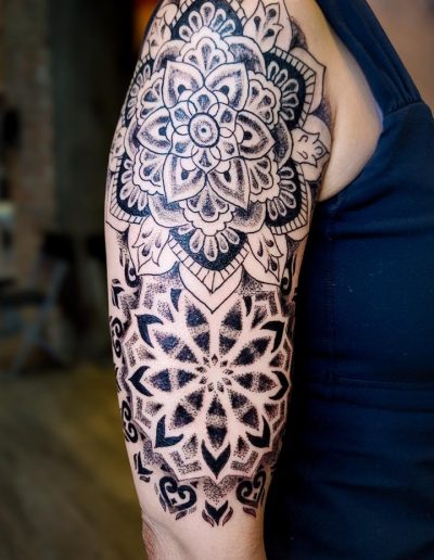 Upper arm features black ink mandala tattoo with intricate floral and geometric patterns.