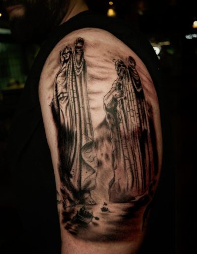 Person's arm displays a black ink tattoo of the Argonath statues and boats from Lord of the Rings.
