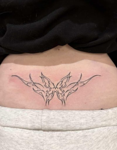 Lower back features a black line art tattoo with a butterfly design and tribal-style flourishes.