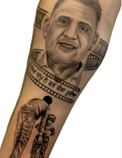 Tattoo on forearm shows portrait surrounded by film strip, text, and a father teaching a child to ride a bicycle.