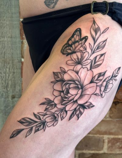 Black and grey floral thigh tattoo with butterfly