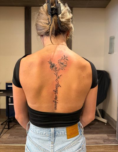 Woman's back tattoo with "Always and forever" script and floral design