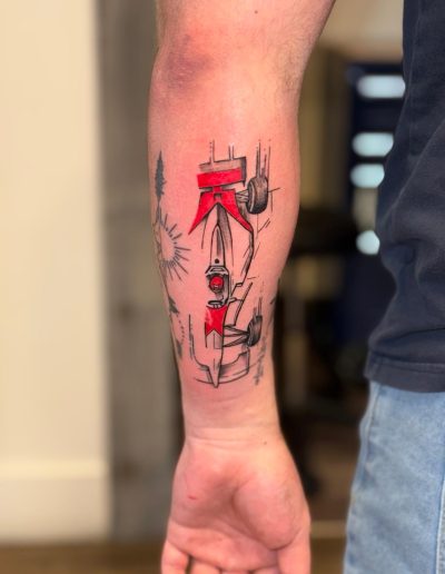 Tattoo of a red and black abstract Formula 1 car on a forearm.
