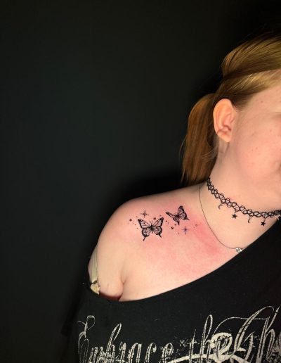 Woman with two small butterfly tattoos on her shoulder and collarbone