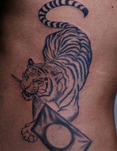 Tiger tattoo holding a flag with a circle on a person's side