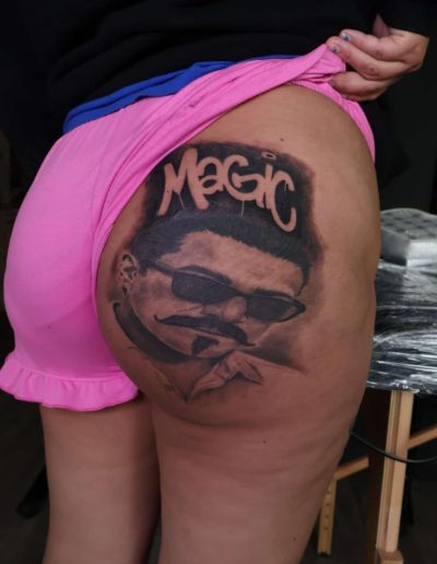 Tattoo of a man with a mustache and sunglasses, with "Magic" written above