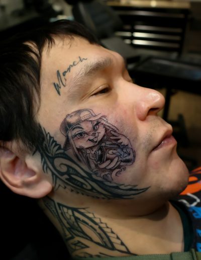 Tattoo artist working on a man's face with a rabbit tattoo