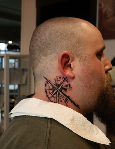 Man with a compass tattoo on his neck, side view