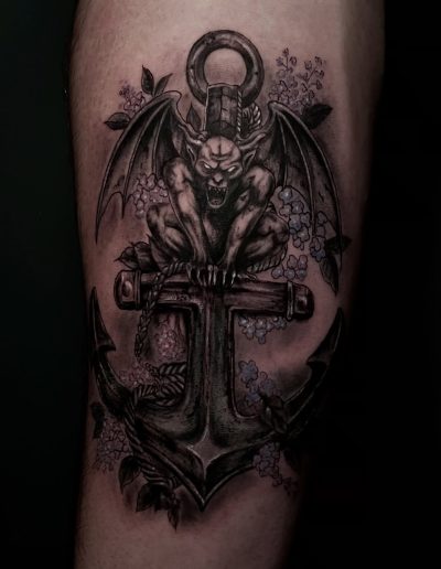 Gargoyle perched on an anchor, surrounded by flowers, detailed tattoo art.