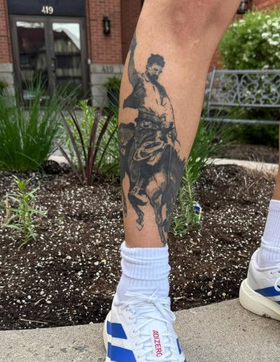 Tattoo of a man on horseback, a classic art style, on a person's leg.