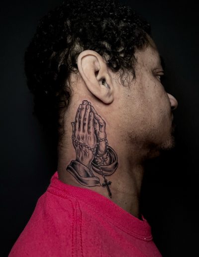 Man with praying hands and rosary tattoo on neck